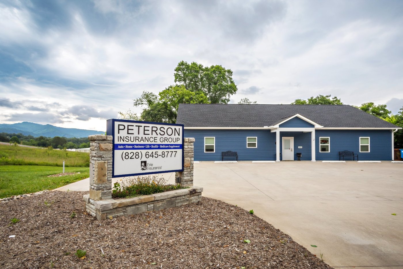 Peterson Insurance Group office in Weaverville, NC with sign showing phone number and Erie Insurance logo, mountains in background